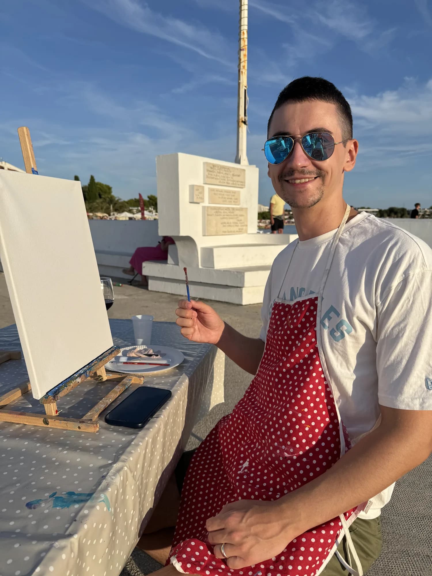 Damjan painting on an easel by the sea
