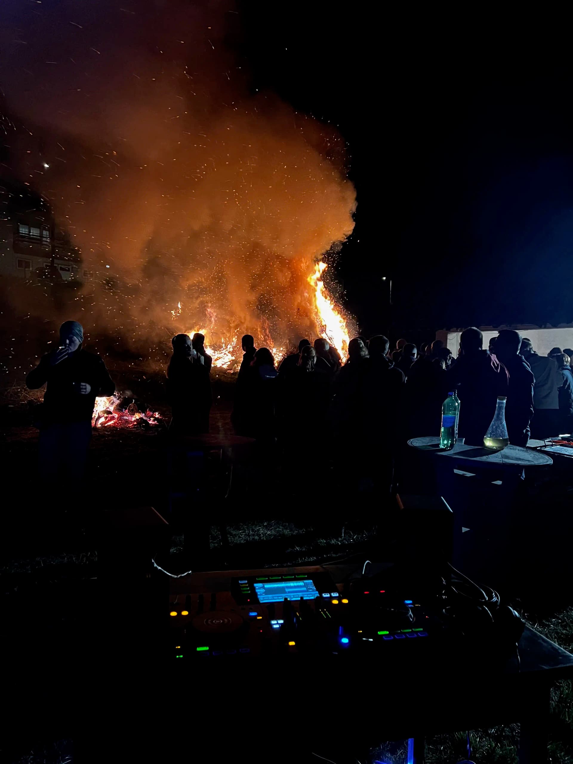 Vuzmenjak Easter bonfire in Draga Svetojanska — crowd silhouetted against the fire with the DJ deck in the foreground
