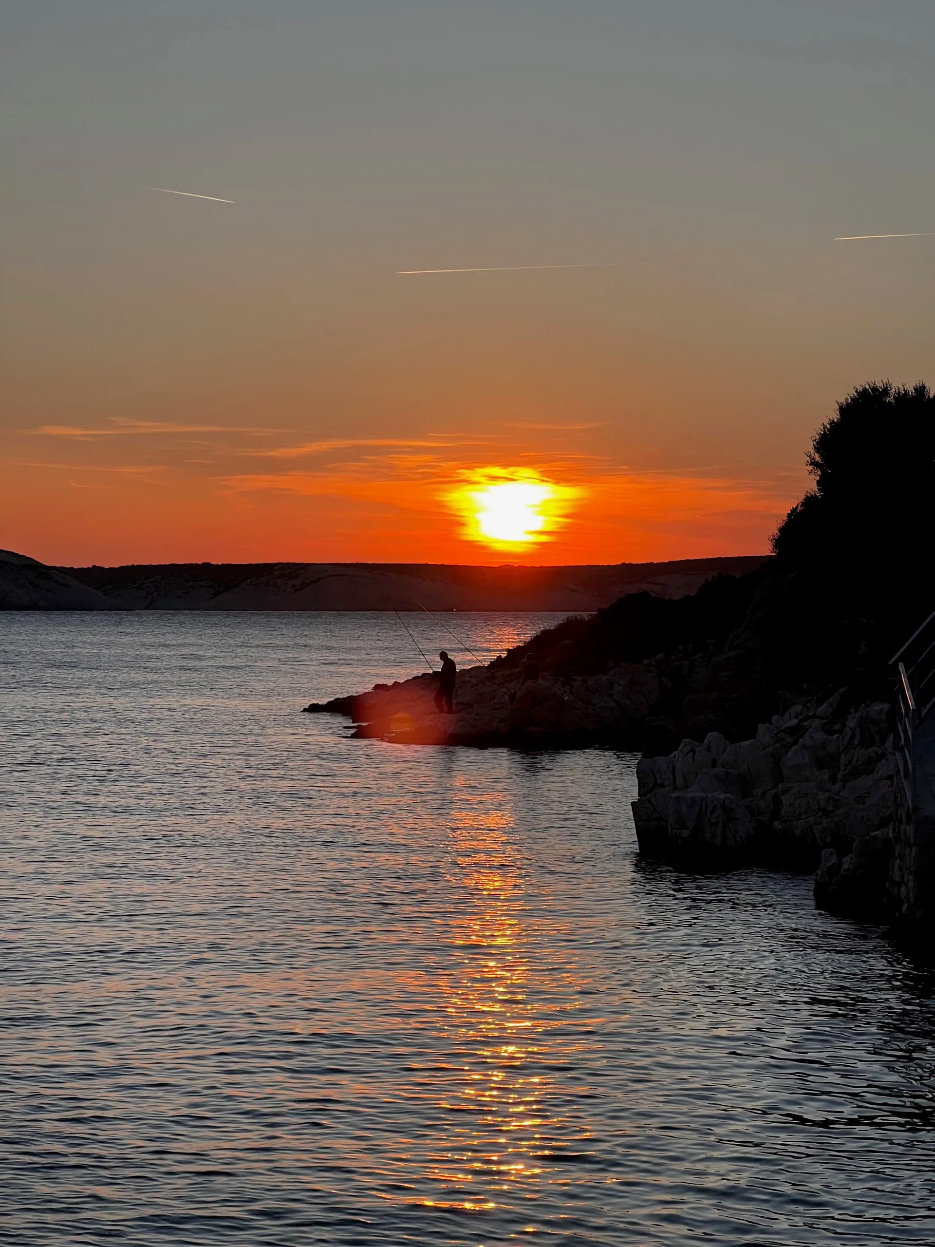 Sunset over the Adriatic with a fisherman silhouetted on the rocks